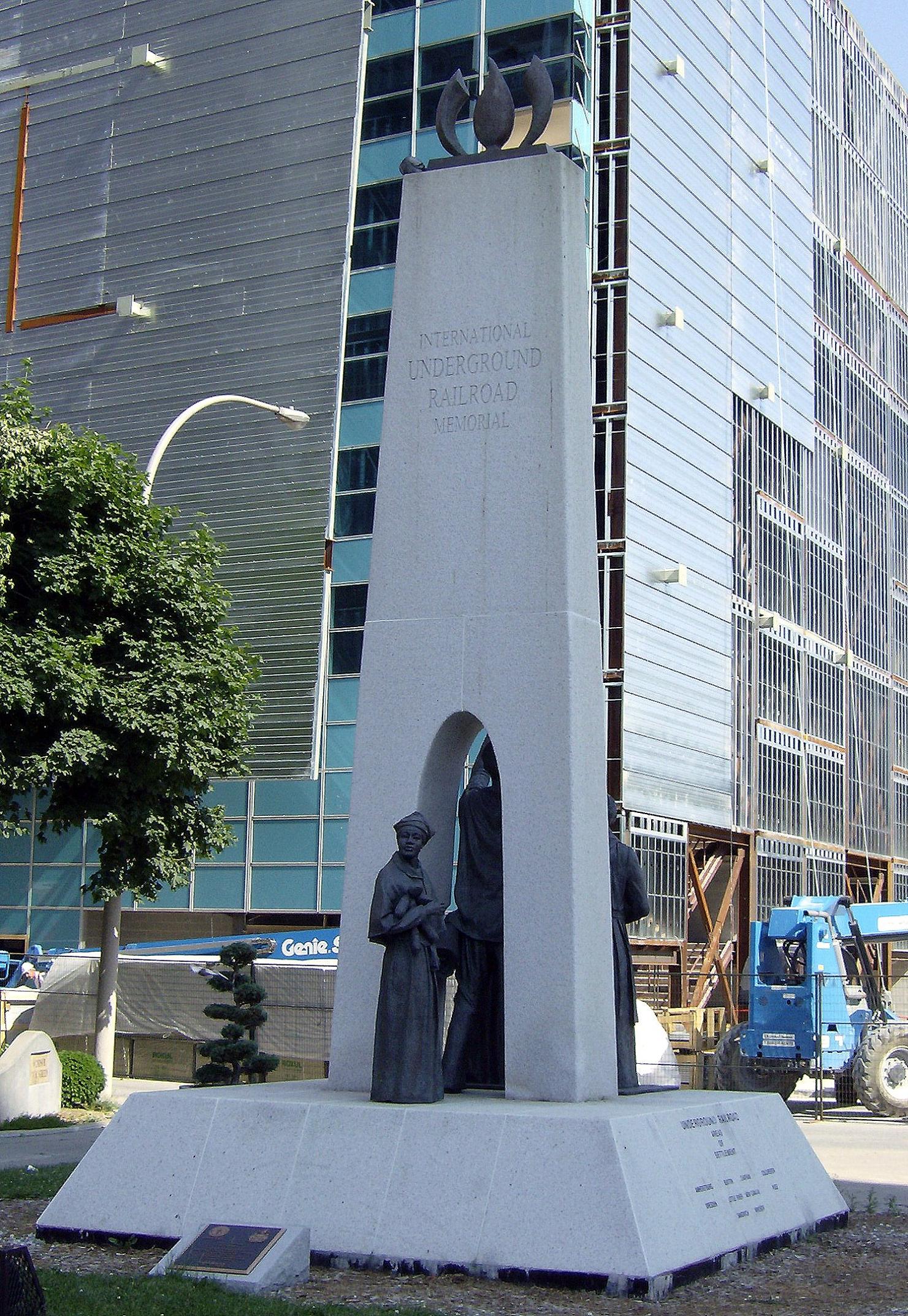 Statue de bronze d'une femme noire tenant un bébé et franchissant le seuil d'une porte en ciment